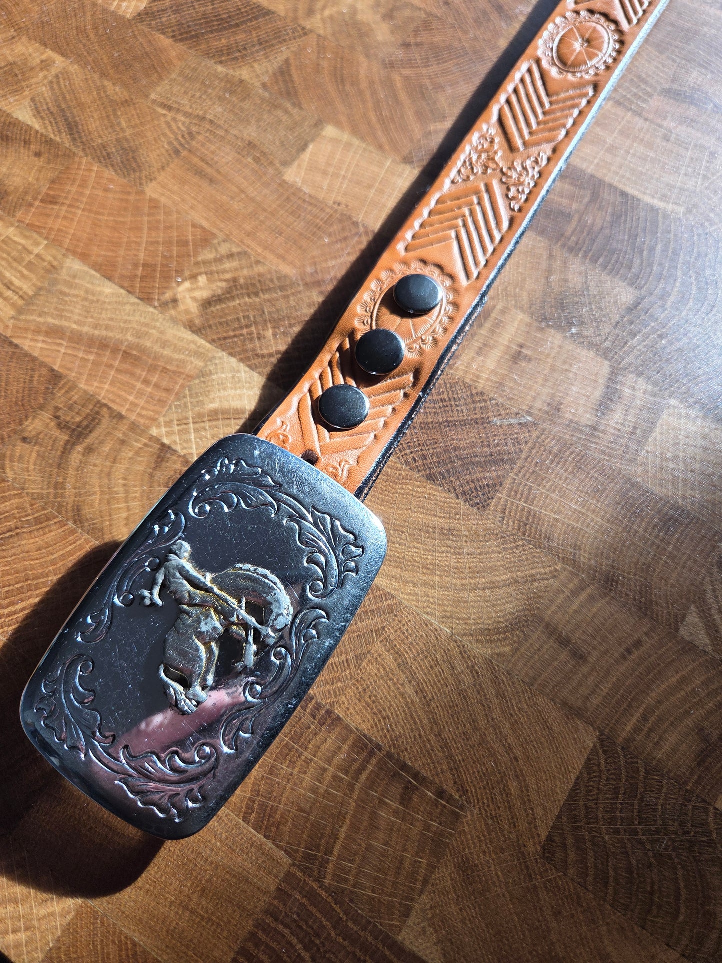 Metal belt buckle with bucking bronco cowboy and tan belt